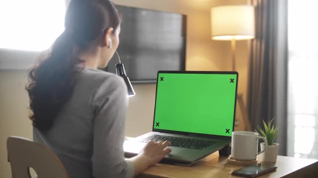 亚洲妇女在家里使用绿色屏幕的笔记本电脑视频下载