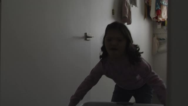 患有唐氏综合症的女孩在洗衣篮里拿着衣服/美国犹他州Lehi视频素材