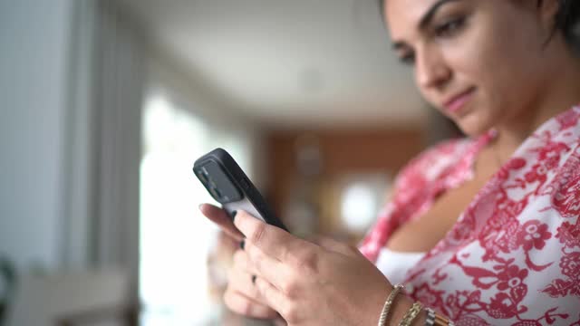 年轻女子在家里用智能手机发短信视频素材