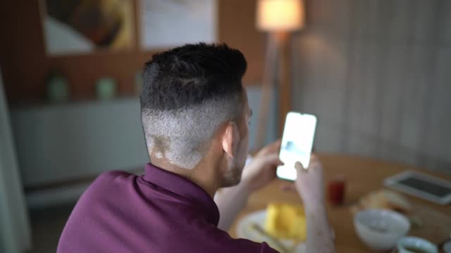 一个年轻人在家里使用智能手机的肖像视频素材