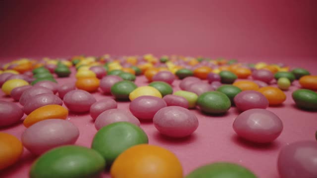 粉色背景上的一堆彩色糖豆糖视频下载