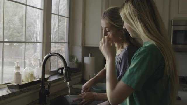 微笑的母亲和女儿在美国犹他州高地厨房洗盘子视频素材