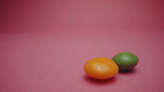 粉色背景上的橙色和绿色软糖视频下载