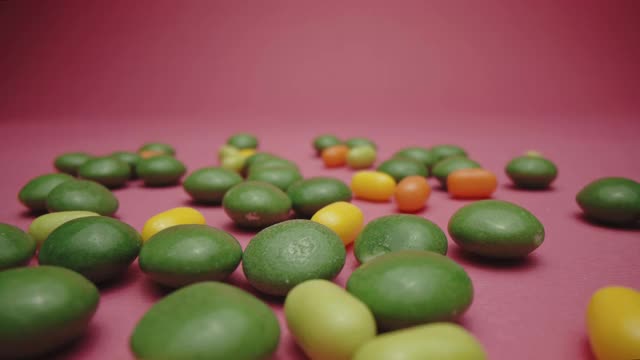粉色背景上的一堆彩色糖豆糖视频下载