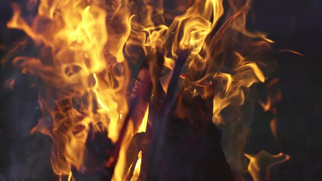 慢镜头4K拍摄木柴在火中燃烧。明亮的橙色营火火焰和白色烟雾。篝火在晚上特写视频素材