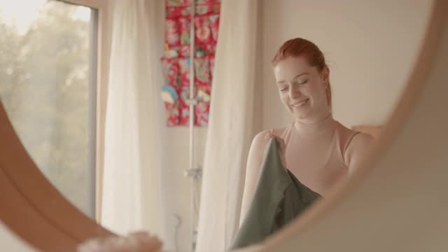 一名年轻女子早晨在浴室的镜子前穿衣服视频素材