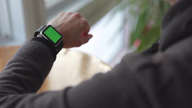 女人戴chroma键绿色屏幕智能手表在办公室的特写视频下载