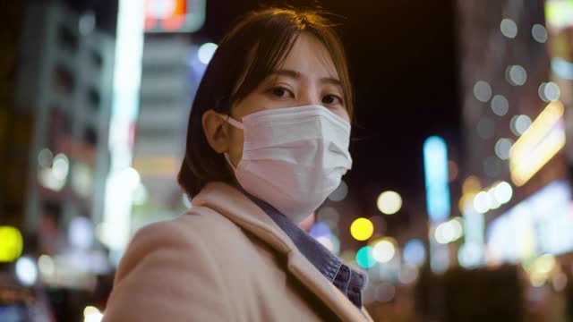 在城市的街道上，一名妇女用面罩遮住脸，严肃地盯着镜头视频下载