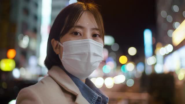 在城市的街道上，一名妇女用面罩遮住脸，严肃地盯着镜头视频素材
