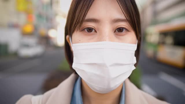 在城市的街道上，一个严肃的女人用面罩遮住脸，严肃地盯着镜头视频素材