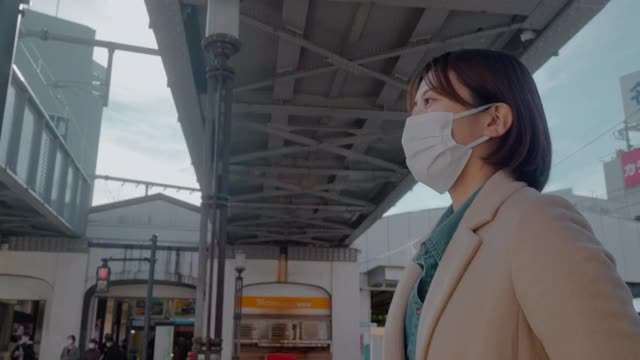 一名妇女戴防护口罩以预防疾病，并在街上行走视频下载
