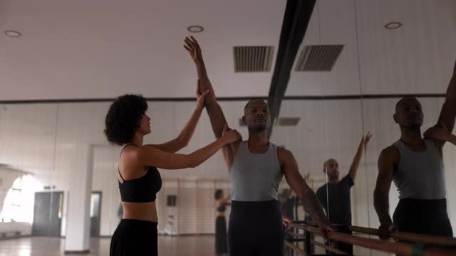 教练在舞蹈工作室调整男舞者的手臂姿势视频素材
