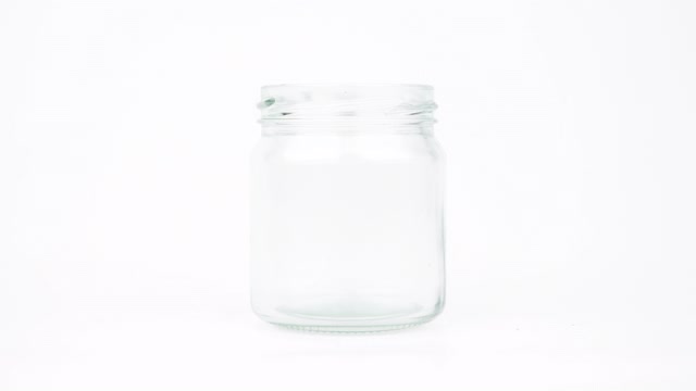 定格动画小红心放入一个透明的玻璃罐中孤立在白色的背景上。视频下载