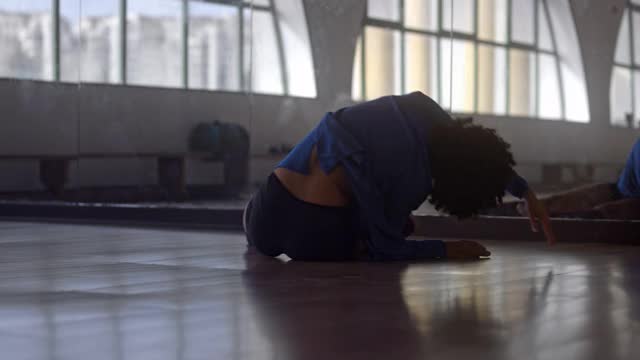 非裔美国妇女躺在舞蹈室的地板上跳舞视频下载