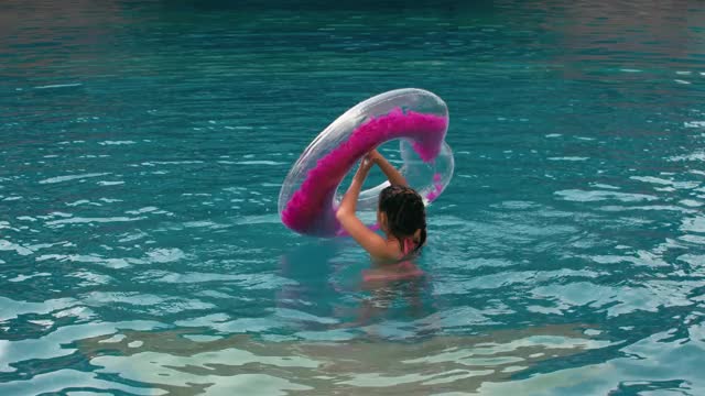 可爱的小女孩在游泳池里玩得很开心。孩子们享受暑假在游泳池里跳跃、旋转、溅水。快乐的童年。视频素材