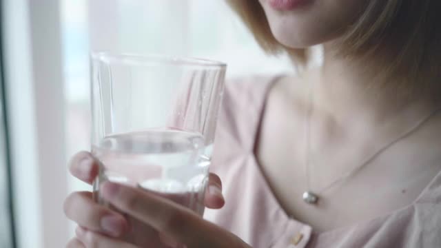 亚洲女人在家里喝水的慢镜头视频素材