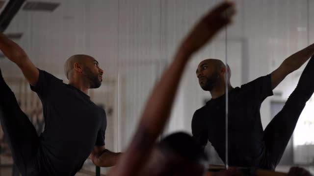男舞者在舞蹈室的杠铃上伸展腿视频素材