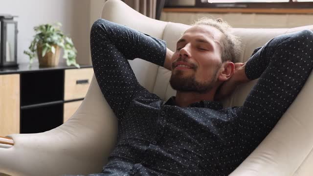 男人闭上眼睛放松地靠在舒适的扶手椅上视频素材