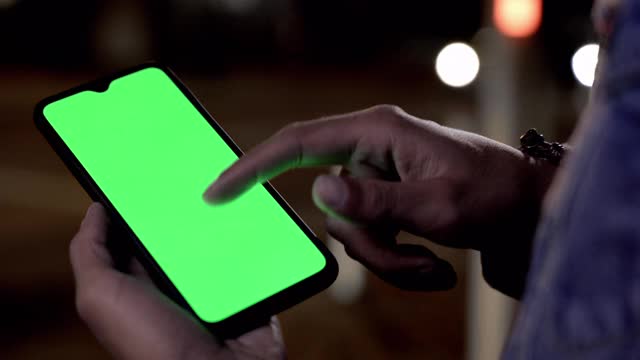 一名男子晚上在户外用绿色屏幕打手机视频下载