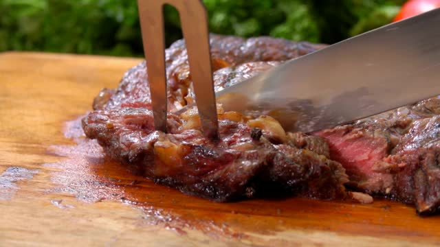 厨师从一块木板上切下一块多汁的牛排视频下载