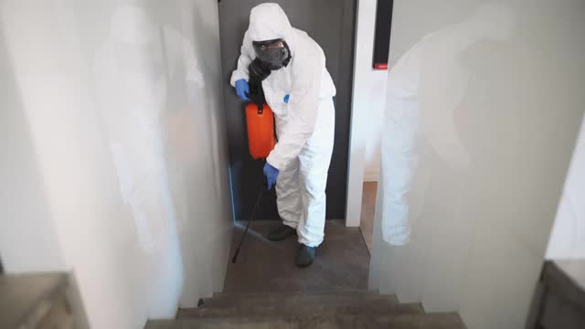 冠状病毒大流行期间，穿着防护服的环卫工人正在对楼梯进行消毒视频下载