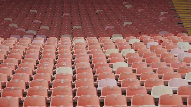 红色的空塑料座位在体育场排成一排。视频素材