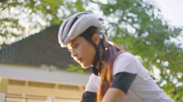 亚洲年轻美丽的女人骑自行车为健康在晚上在公共公园。运动员健康和坚定的女孩在运动服装锻炼通过自行车锻炼运动为她的健康健康。视频下载
