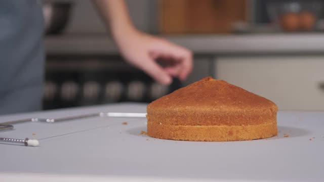 糕点师用特制的切刀将烤好的蛋糕切成平铺一层。视频下载