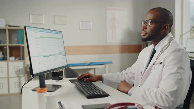 穿着白大褂的富有经验的非裔美国男医生在办公室用个人电脑工作。医疗保健专业人员处理测试结果，病人治疗计划。视频素材