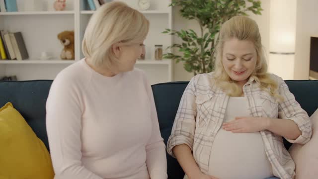 高兴女人摸着怀孕的肚子，感觉宝宝的运动，友谊亲密视频素材