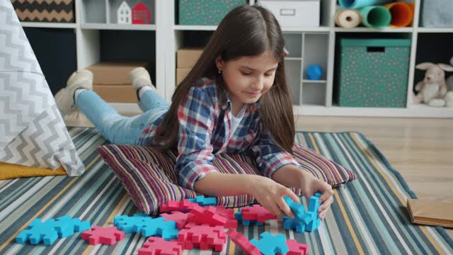 可爱的孩子躺在孩子房间的地毯上玩玩具，专注于有趣的游戏视频下载