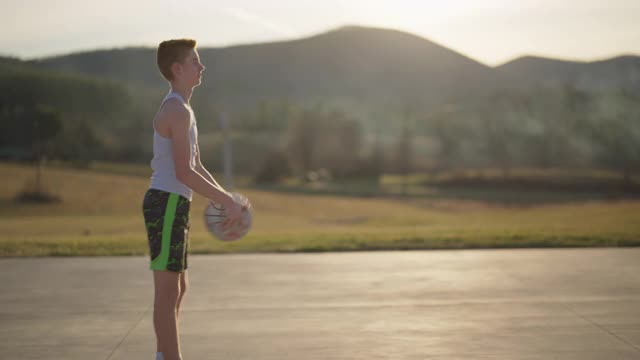 一个自信的男孩在山区外面打篮球视频素材