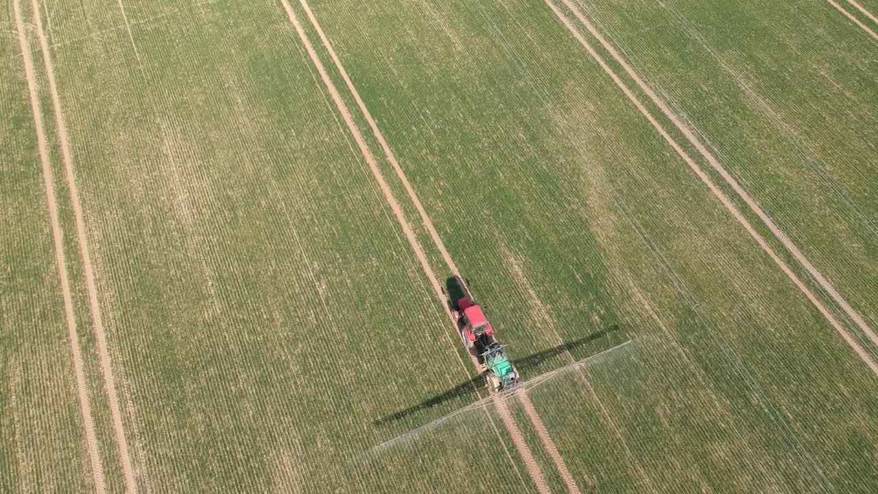 农用拖拉机用喷雾器喷洒春季作物田、空中视频素材