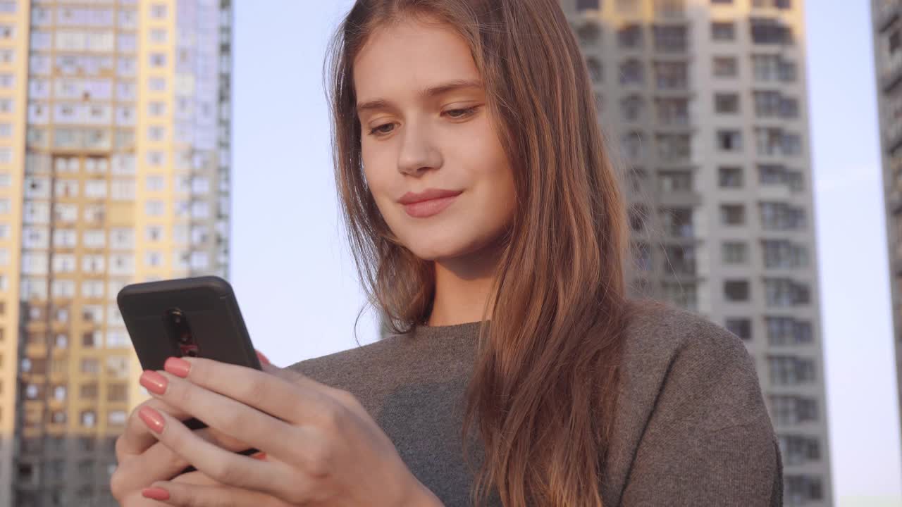 微笑的年轻女子使用视频信息社交网络在建筑外部背景视频素材