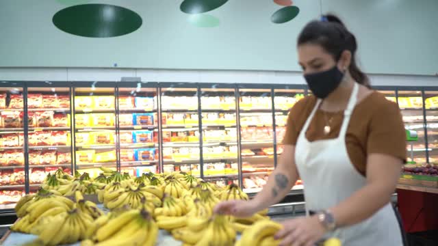 年轻女子戴着口罩在超市安排水果视频下载