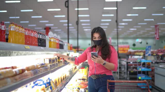 年轻女子戴着口罩在超市买奶酪视频素材