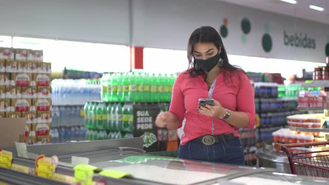 年轻女子戴着口罩在超市买速冻食品视频素材
