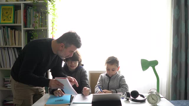 父亲们正在帮助孩子们完成家庭作业。视频素材