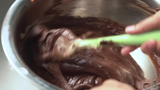 一个女人用电动手搅拌机在一个碗里搅拌原料视频下载