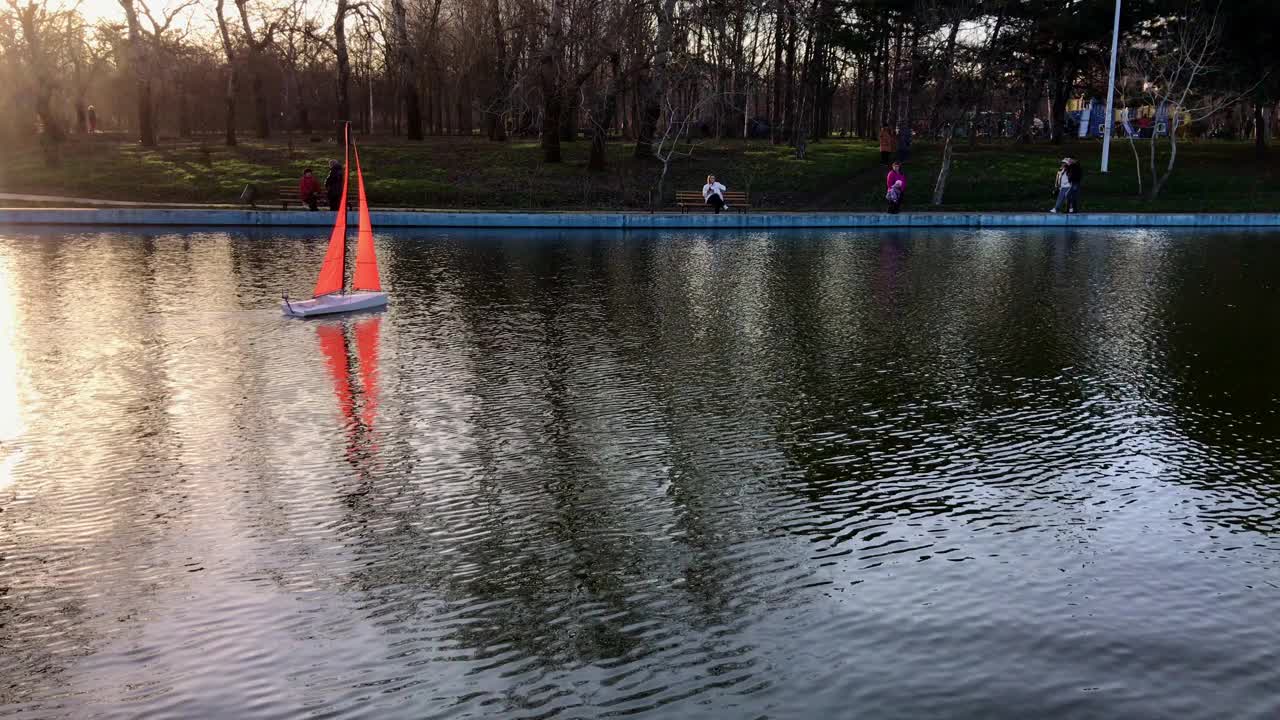 美丽的手工帆船在一个公园的池塘里游泳。视频素材