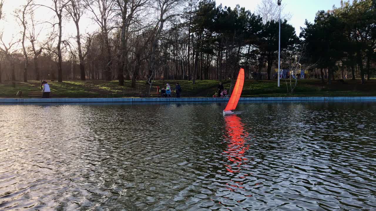 美丽的手工帆船在一个公园的池塘里游泳。视频素材