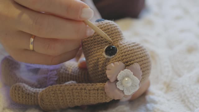 特写女性的手做一个钩针玩具，并设置眼睛在口吻玩具狗使用一个木制钩视频下载