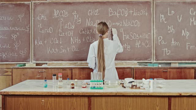 女科学家在实验室工作，她在工作台上的黑板上记录公式视频下载