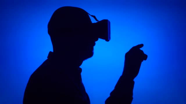 戴VR 360眼镜的老人的黑色剪影。蓝色背景上的男性轮廓视频素材