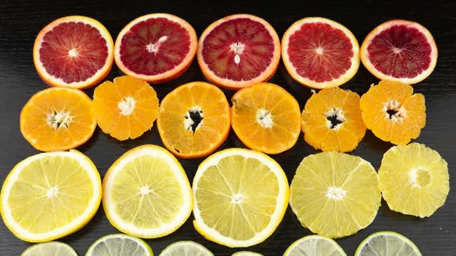在一张黑色的桌子上放着柑橘类水果。柠檬，酸橙，橙，血橙，柑橘视频素材