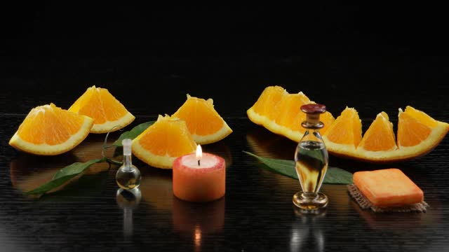 香薰与橙油。香薰灯，橙色的水果，橙色的肥皂，装有橙色油的瓶子放在黑色的木桌上视频下载