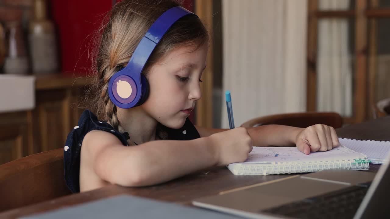 小女孩戴着耳机在笔记本电脑上学习音频课程视频下载