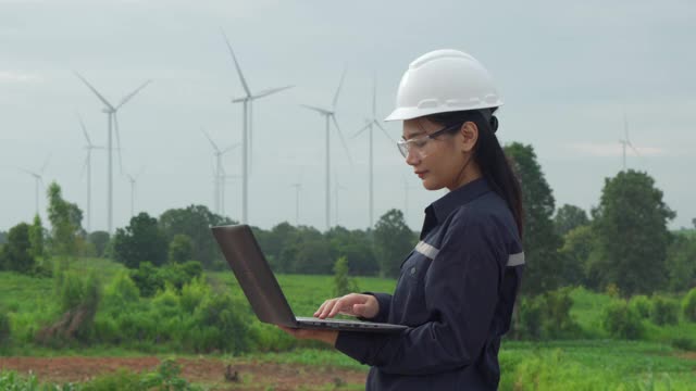 在泰国风电场，检查工程师正在用笔记本电脑准备和检查风力涡轮机的进度。视频下载