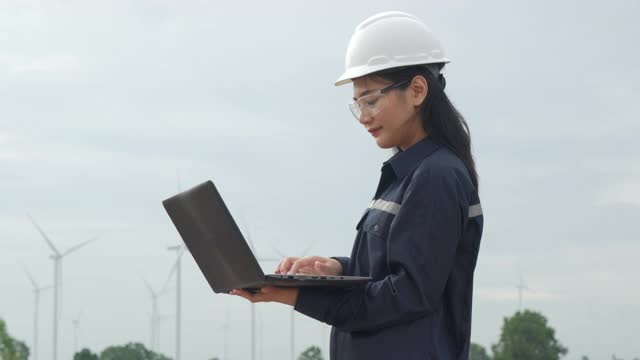 在泰国风电场，检查工程师正在用笔记本电脑准备和检查风力涡轮机的进度。视频素材