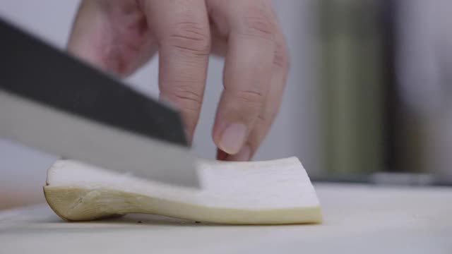 SLO MO:特写厨师的手将王牡蛎或eringi蘑菇切成条纹。视频下载